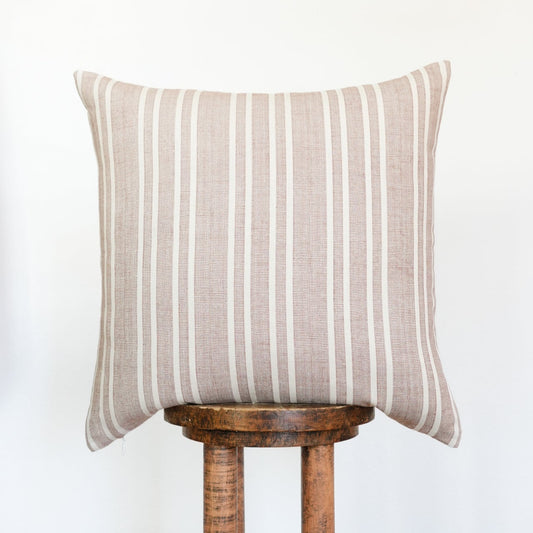 Striped pillow on a wooden stool against a white background